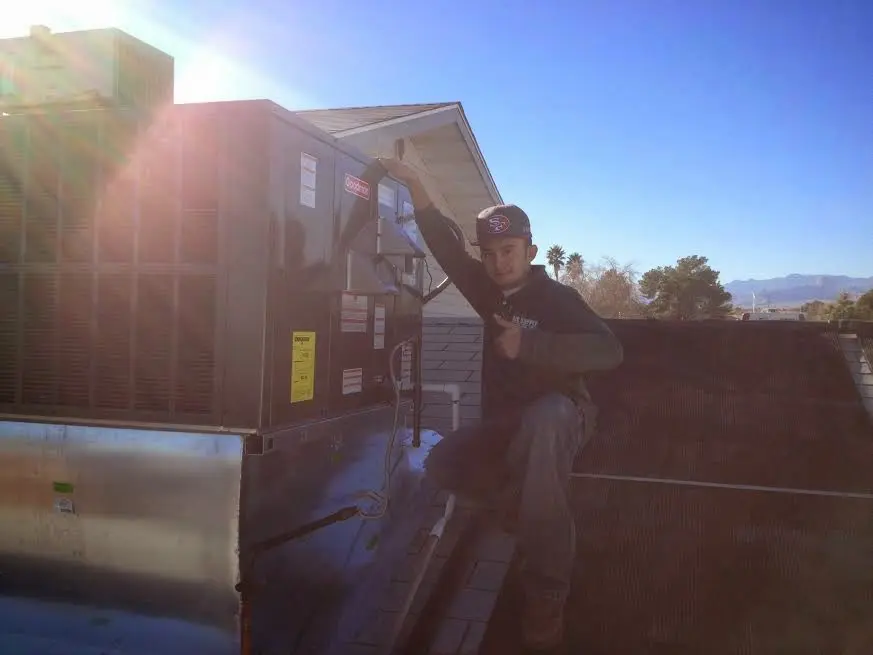 HVAC technician performing Air Duct Cleaning on a rooftop unit in West Athens