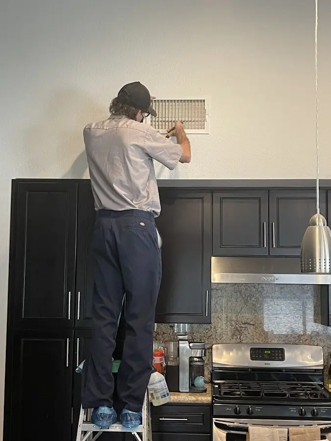Technician inspecting an air vent during HVAC service in West Athens